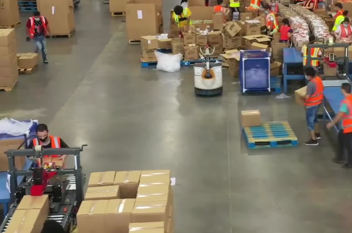 Workers in orange hi-vis vests packing boxes on a bright modern floor